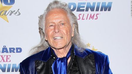 Peter Nygard in a blue suit and coat poses for a picture.